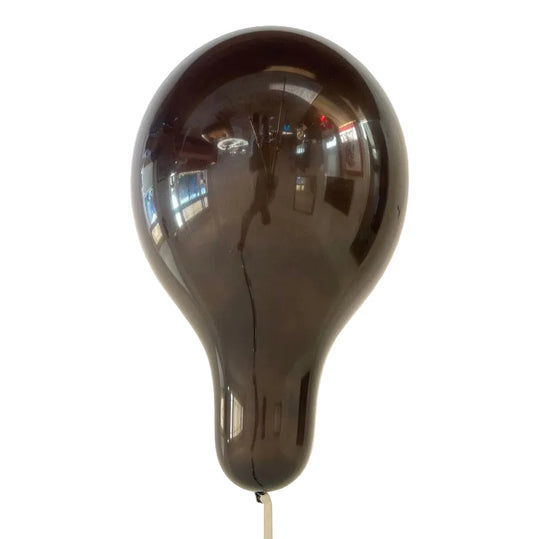 A helium filled black balloon against a white background.